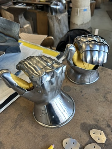 Steel gauntlets and helmet components arranged on a workshop bench