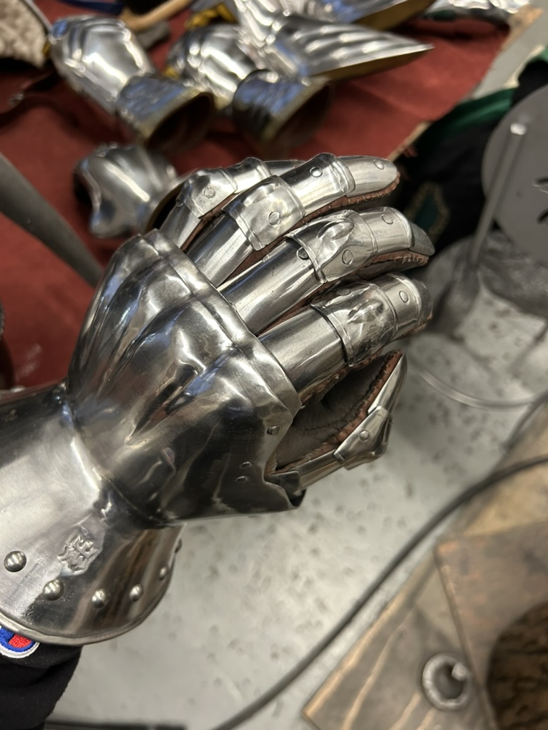 Close-up of a polished steel gauntlet with articulated fingers and leather edging