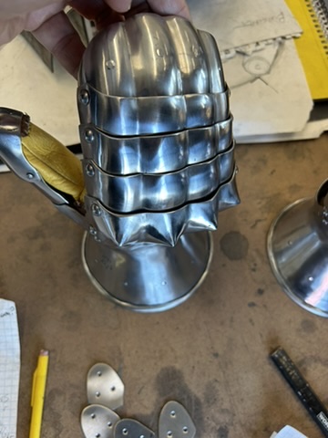 Segmented steel helmet piece with pointed face guard in progress